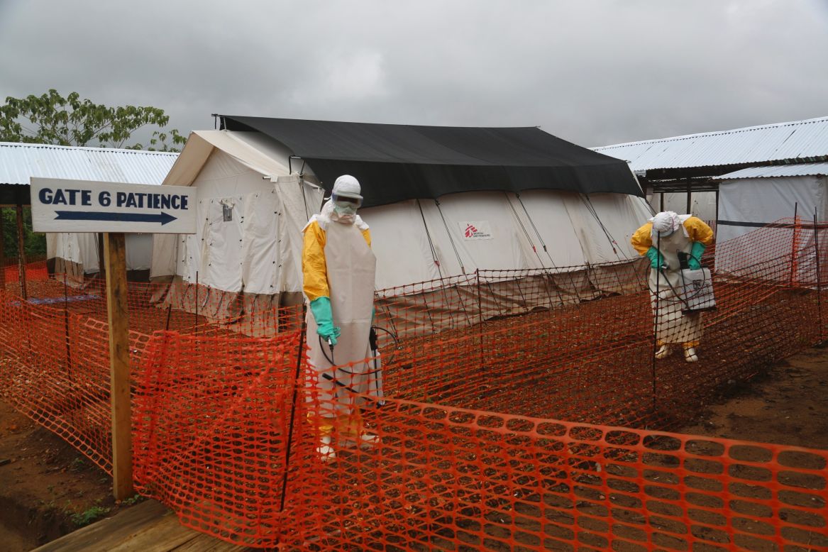 At MSF's main treatment center for Ebola patients in Kailuhun, workers dressed in protective suits spray the entrance area with chlorine.