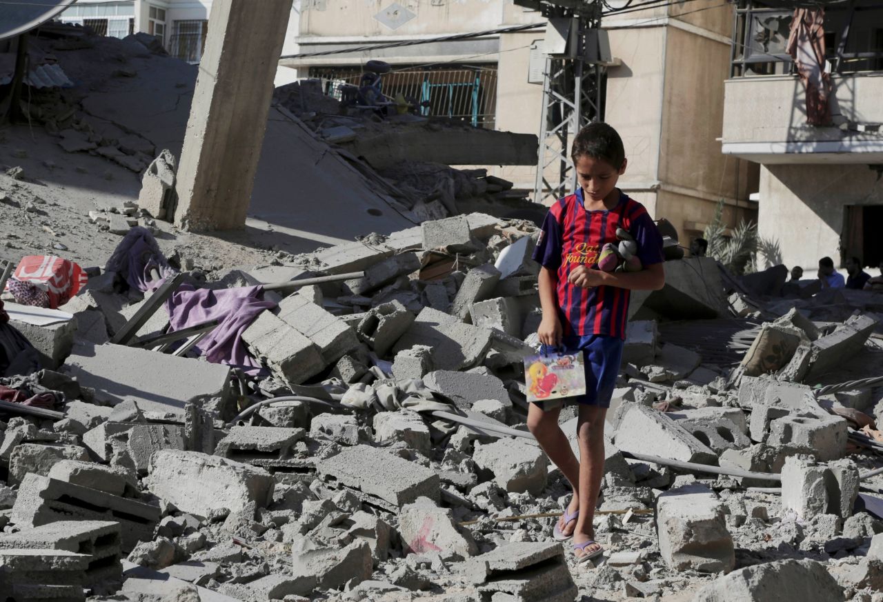 A Palestinian boy salvages family belongings from the rubble of a four-story building after an airstrike in Gaza City on Friday, August 8.