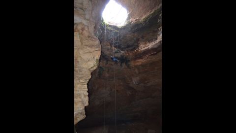 Justin Sipla ascends a rope dangling from 80 feet after working at the bottom of the cave.