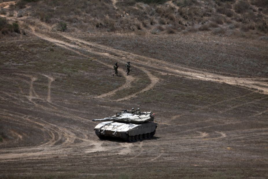 Israeli soldiers walk past a Merkava tank as they patrol a field near Israel's border with Gaza on August 9.