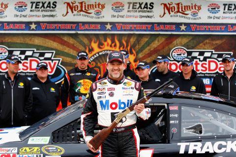 Stewart poses with a rifle awarded to him after qualifying for pole position at a race in Fort Worth, Texas, in April 2014.