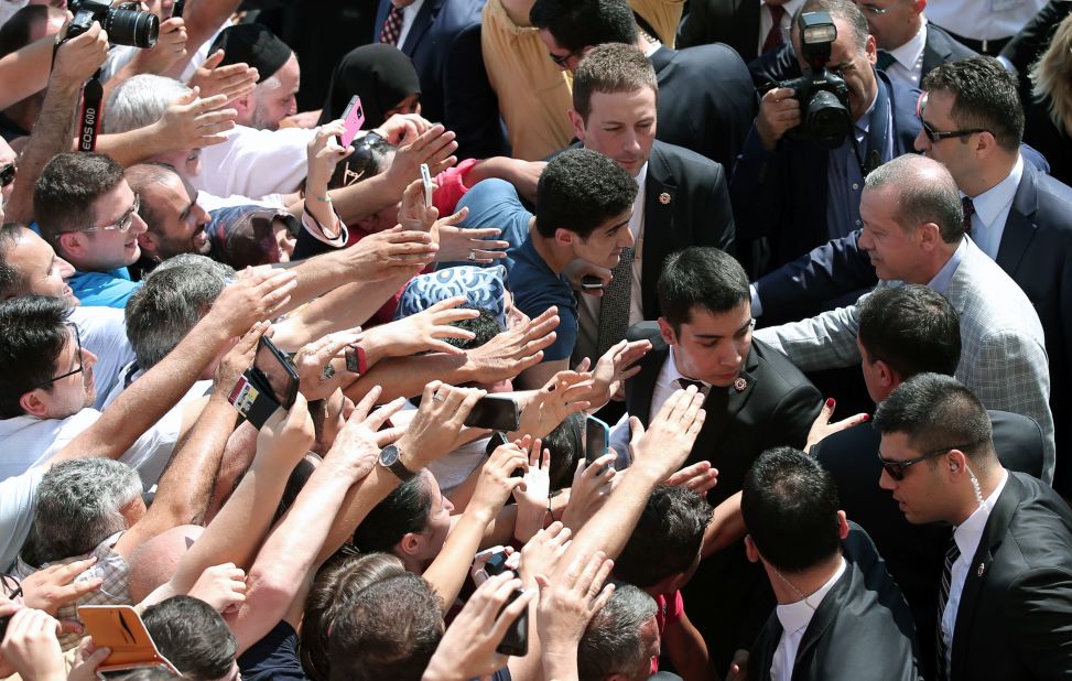Erdogan shakes hands with cheering supporters outside an Istanbul polling station on August 10. 