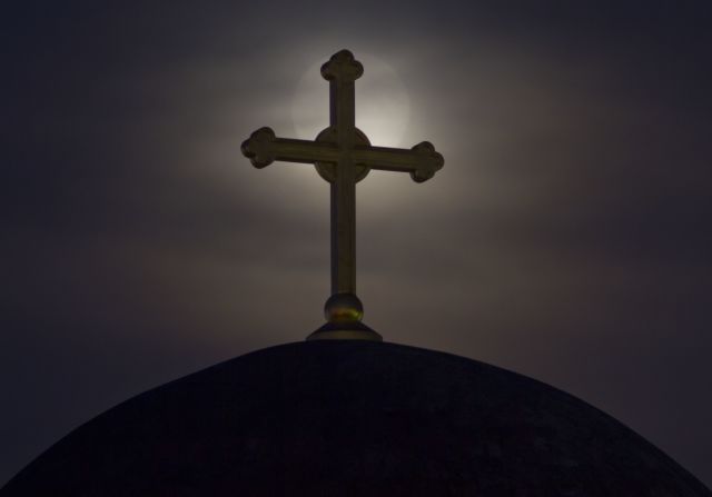 A cross on the unfinished Serbian Orthodox Christ the Saviour Cathedral in Pristina, Kosovo, obscures the moon.  