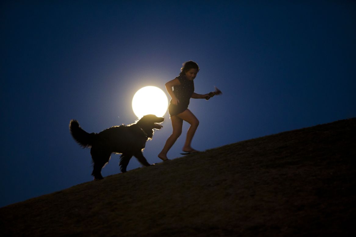 A girl plays with a dog in the light of the moon in Madrid, Spain. 