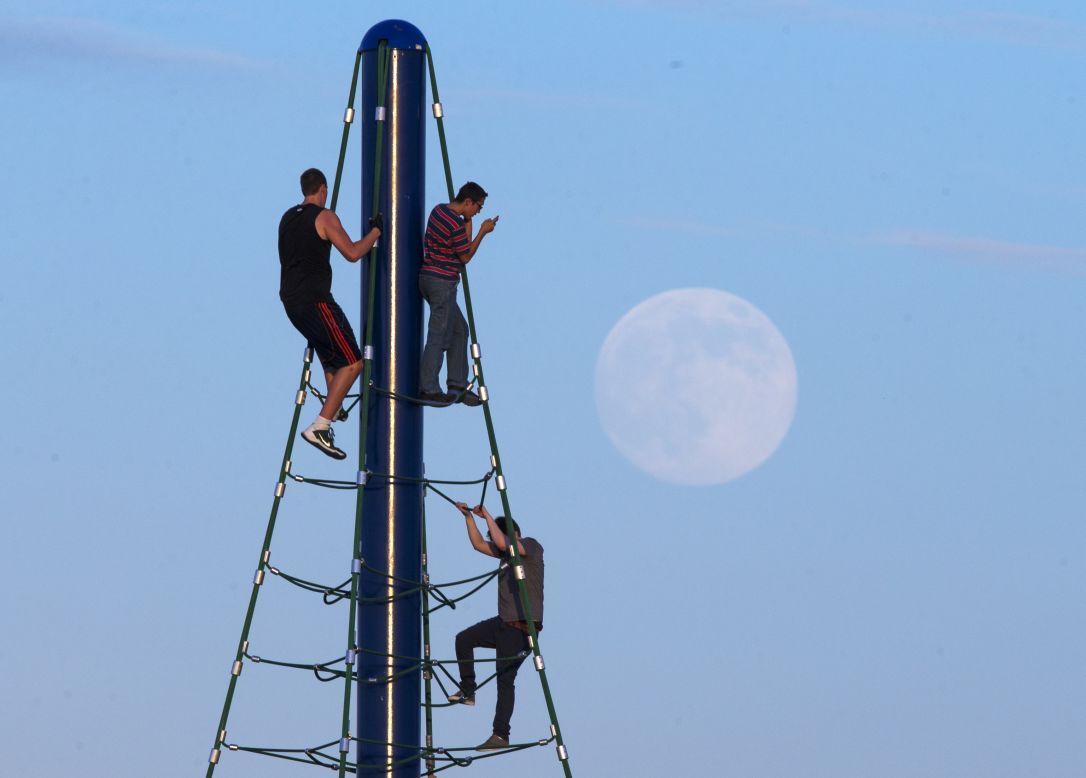 Men play on a climbing structure at Riverview Park in Mesa, Arizona, while the moon rises August 9.