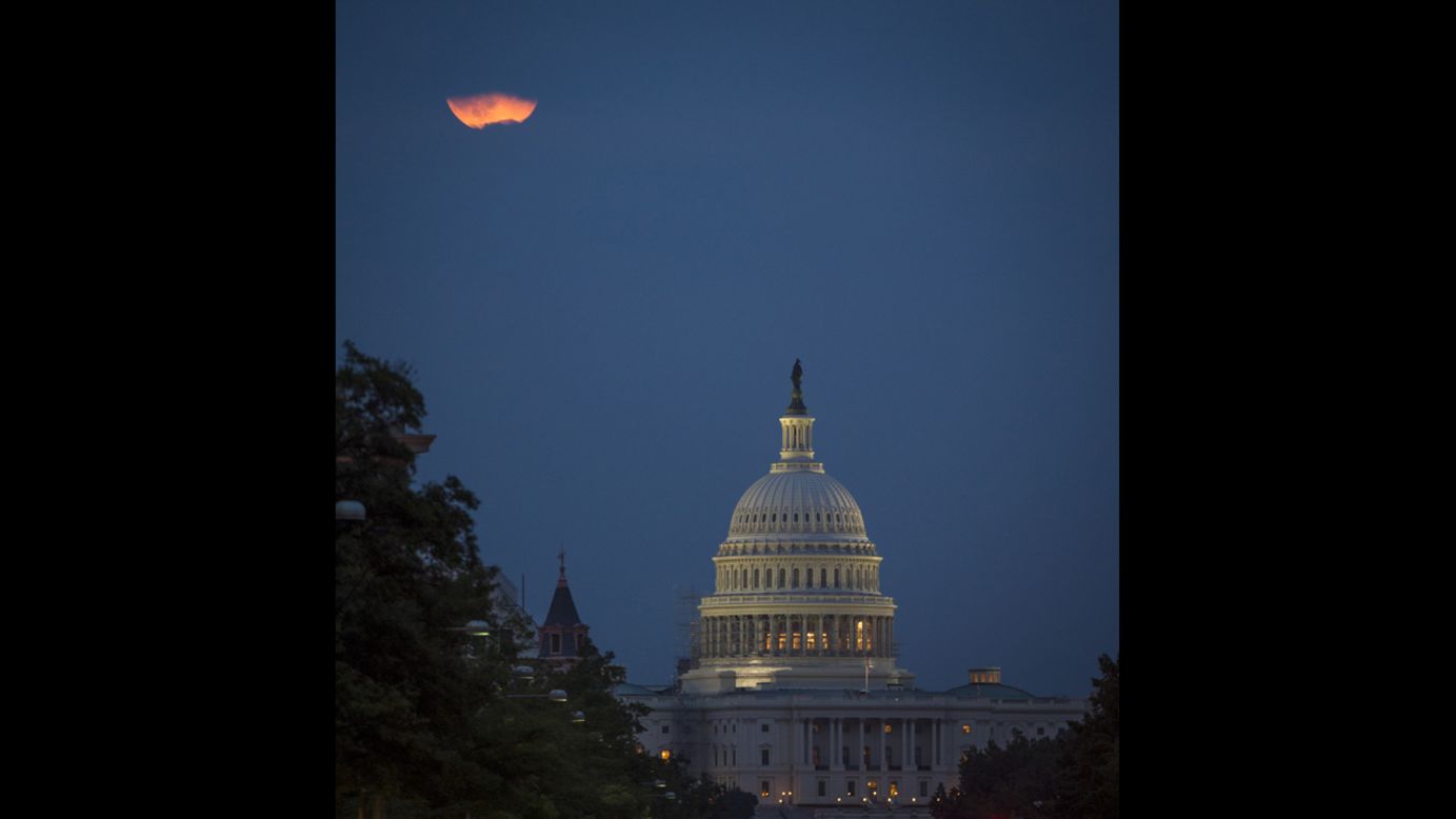 The moon appears behind clouds over the U.S. Capitol in Washington.