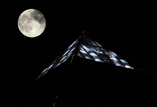 The moon rises behind the light on top of the Luxor Hotel and Casino in Las Vegas.