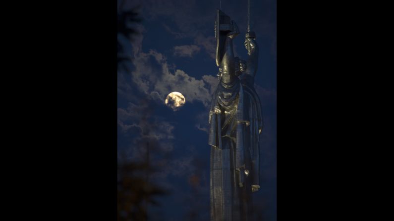 The moon is visible through clouds behind the Motherland statue, part of a World War II memorial complex, in Kiev, Ukraine.