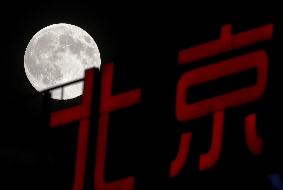 The moon rises over a sign in Beijing on August 10.