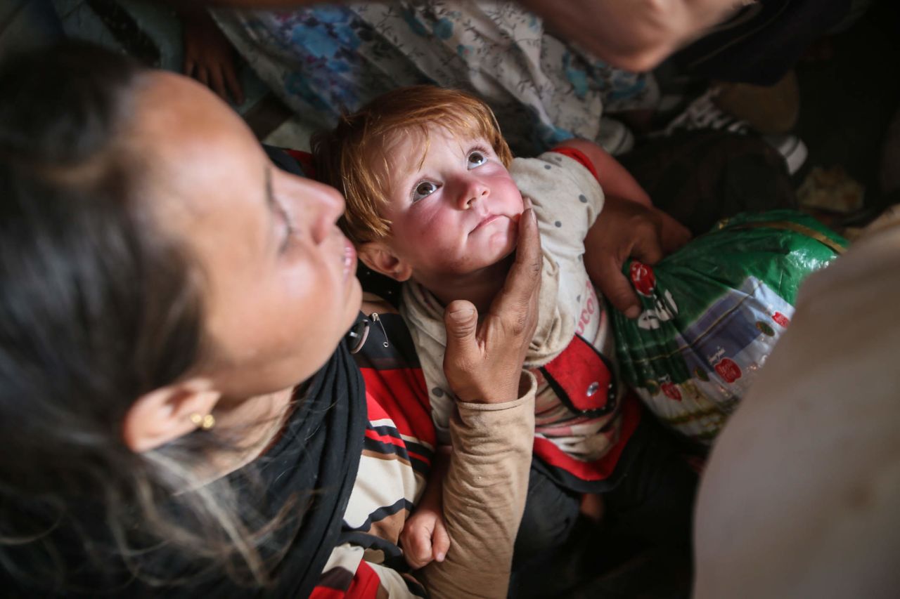 A toddler named Helen sits in her mother's lap after being rescued.