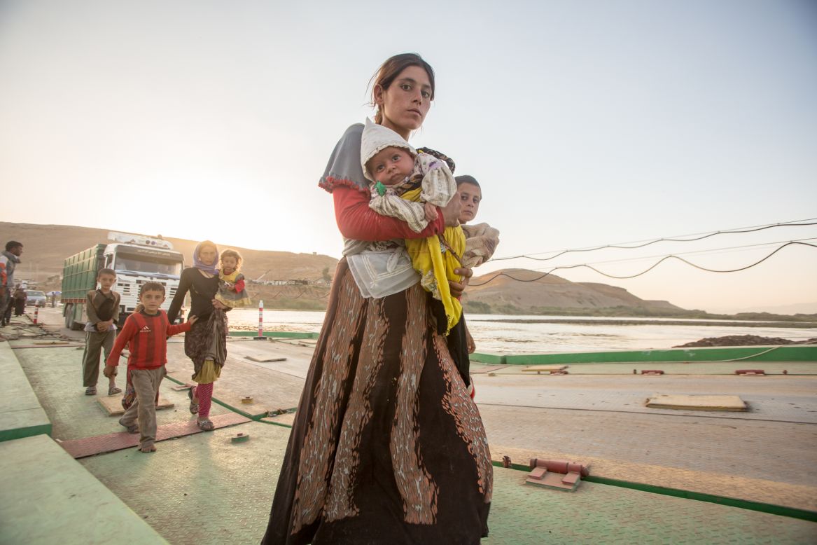 A Yazidi woman holds her baby while crossing Peshkhabour bridge from Syria back into Kurdish-controlled Iraq on Tuesday, August 12.