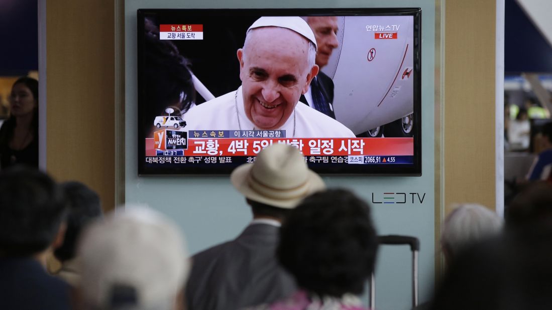 People watch Pope Francis' arrival on a television at the Seoul Railway Station.