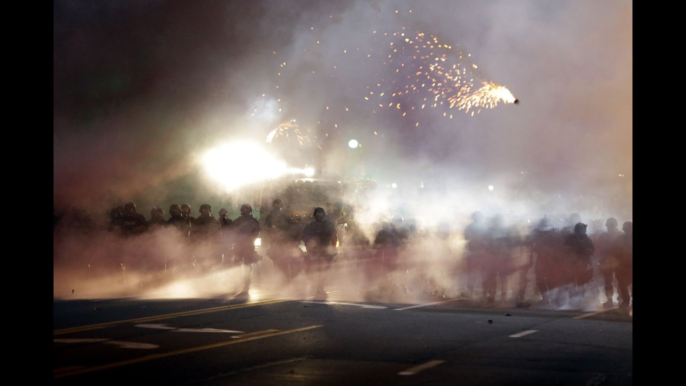 Police stand in clouds of smoke as they clash with protesters on August 13, 2014.