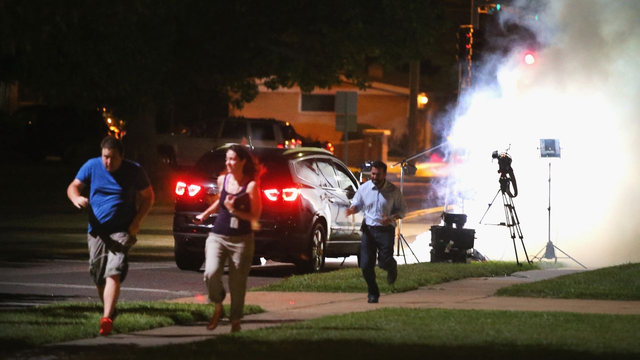 An Al-Jazeera television crew runs for cover as police fire tear gas at their position in Ferguson, Missouri, on August 13.
