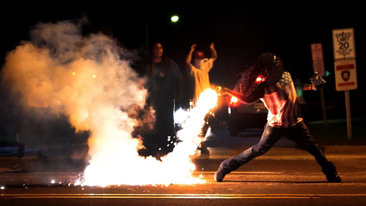 A protester throws a tear gas canister back toward police on August 13, 2014.