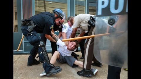 Police officers arrest a man who refused to leave when police cleared streets in Ferguson on August 11, 2014.