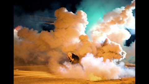 A protester runs from tear gas exploding around him on August 13, 2014.