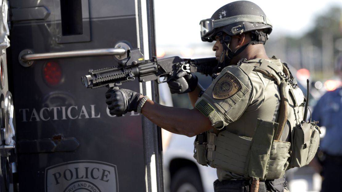 A member of the St. Louis County Police Department points his weapon in the direction of a group of protesters in Ferguson on Wednesday.