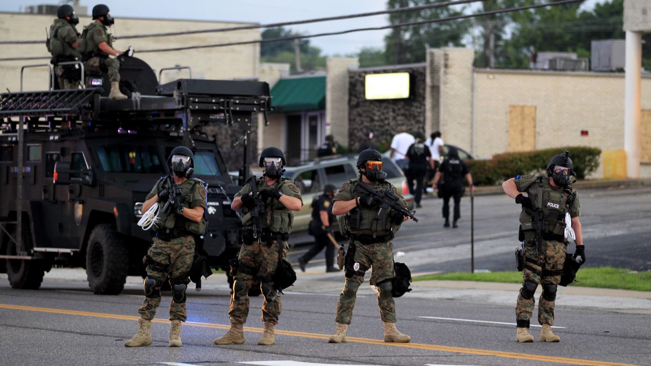 Police wearing riot gear try to disperse a crowd Monday, August 11.