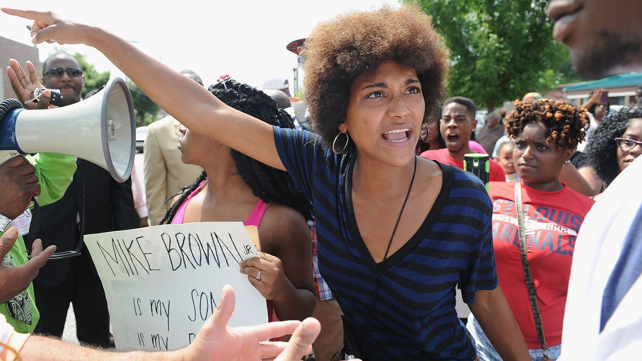A woman tries to calm an emotional protester during a demonstration outside the headquarters of the Ferguson Police Department on August 11, 2014.