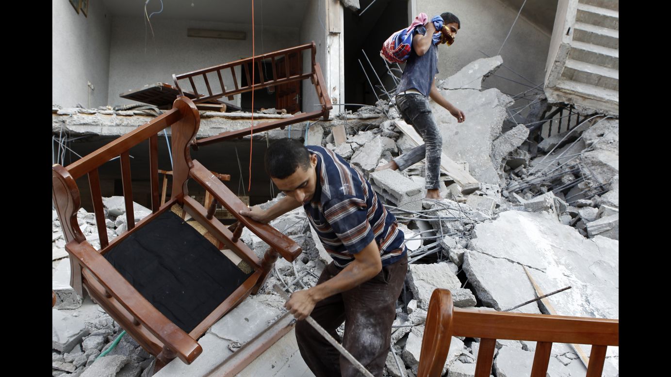 Men salvage belongings from the ruins of a Gaza City home that residents say was hit by an Israeli airstrike on Saturday, August 9.