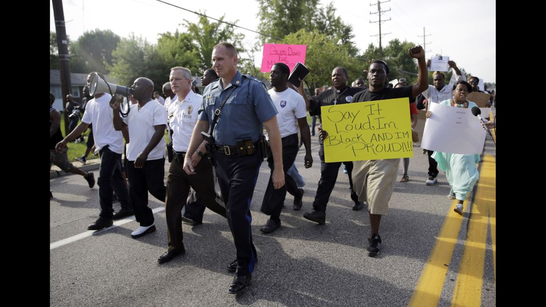 Thousands of demonstrators march down a Ferguson street with members of the St. Louis County Police and the Missouri State Highway Patrol on Thursday, August 14, 2014. 