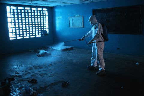 A health worker disinfects a corpse after a man died in a classroom being used as an Ebola isolation ward August 15, 2014, in Monrovia.