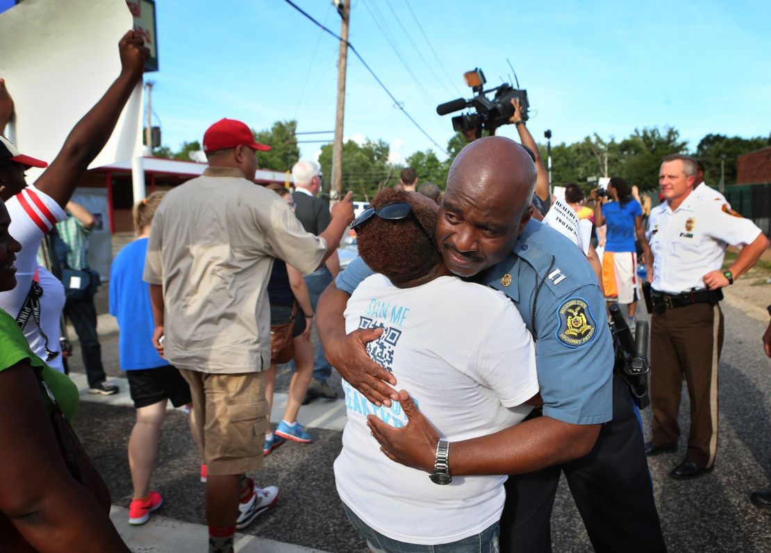 Missouri State Highway Patrol Capt. Ron Johnson gets a hug from Angela Whitman as protesters march on  Aug. 14.