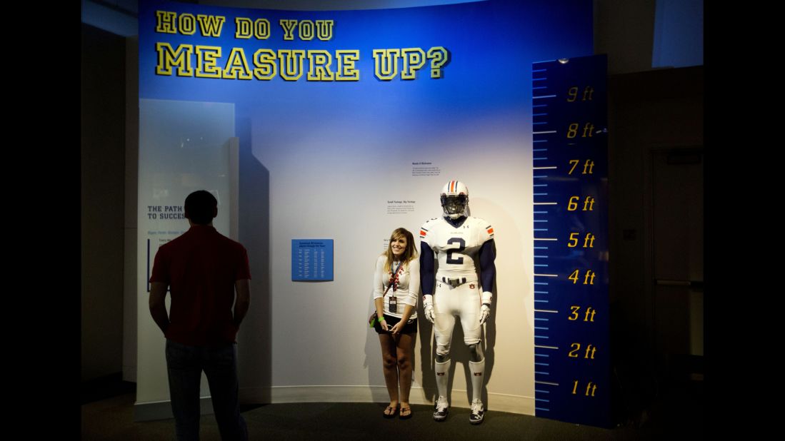 Joanna Jinright measures herself next to a life-size mannequin of a football player dressed like Auburn's Cam Newton.