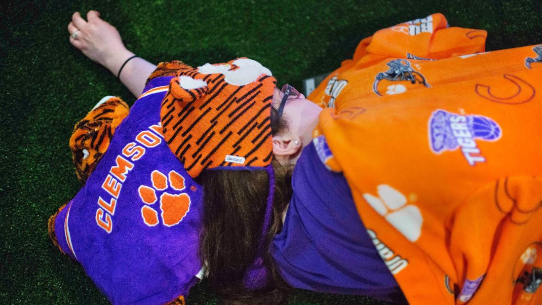 Clemson fan Amelia Stefanelli sleeps on a turf football field at the Hall of Fame. After touring the exhibits, guests were served dinner on the field before settling in for the night as college football-themed movies such as "Rudy" played.