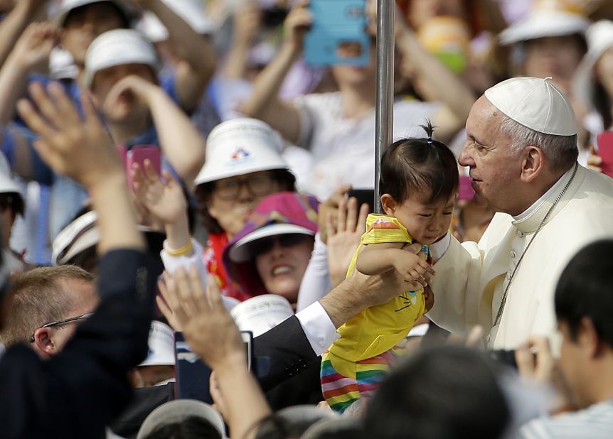 Pope Francis kisses a baby as he arrives to celebrate Mass and the beatification of Paul Yun ji-Chung and 123 martyrs, at Gwanghwamun Gate in Seoul on Saturday, August 16. 
