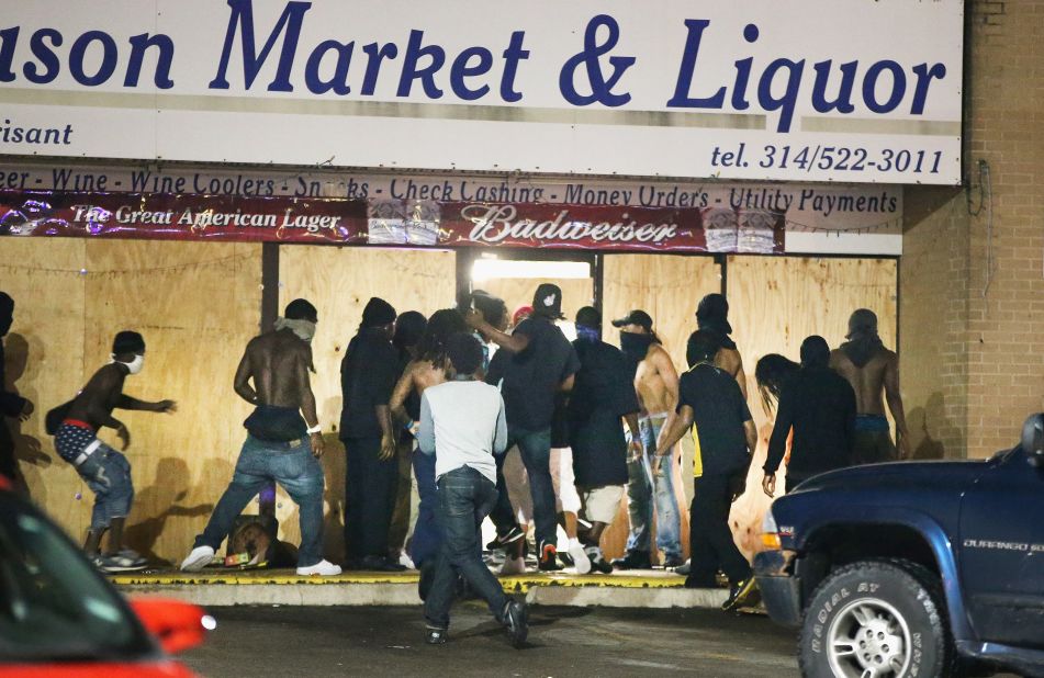 People loot the Ferguson Market and Liquor store on August 16, 2014. Several businesses were looted as police held their positions nearby.