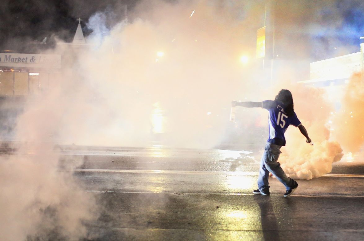A demonstrator throws a tear gas canister back at police on August 15, 2014.