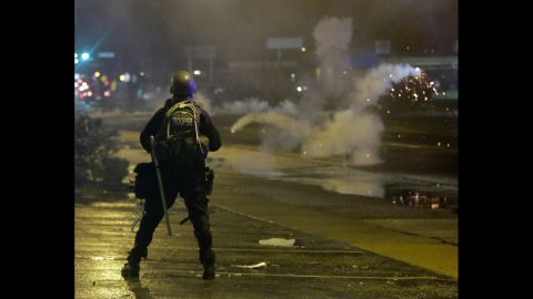 A law enforcement officer watches as tear gas is fired to disperse a crowd on August 17, 2014.