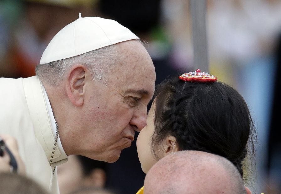 Pope Francis kisses a child on August 17 upon arrival for the mass.
