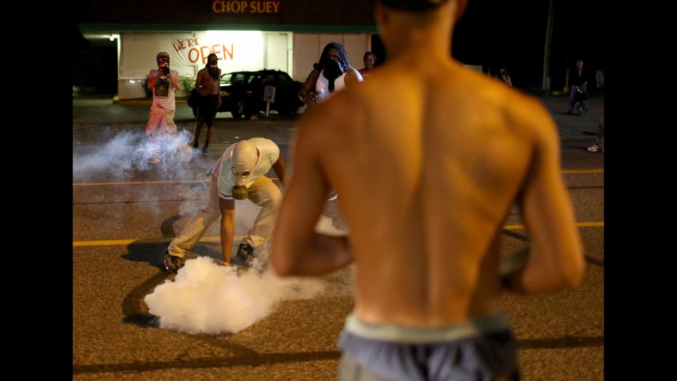 A protester picks up a tear gas canister on Sunday, August 17, 2014.