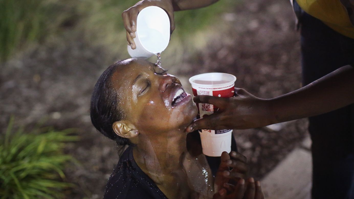 Water gets poured into a woman's eyes after a tear gas attack by police on August 17, 2014.
