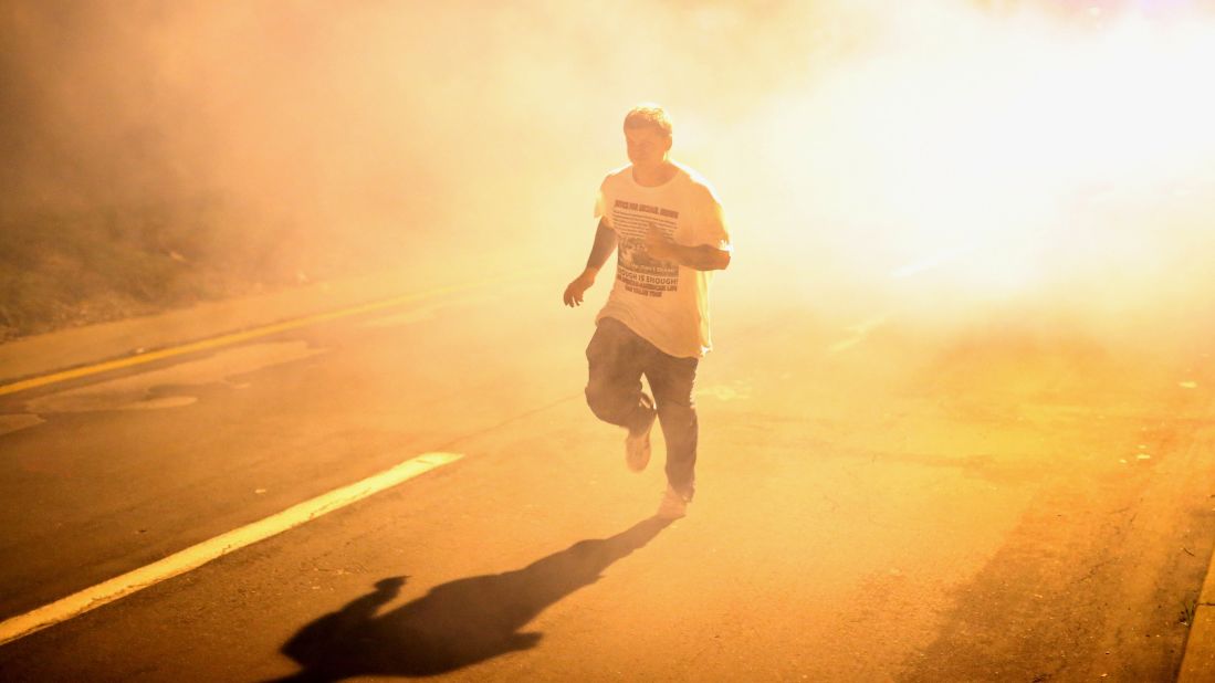 A man runs through clouds of tear gas on August 17, 2014.