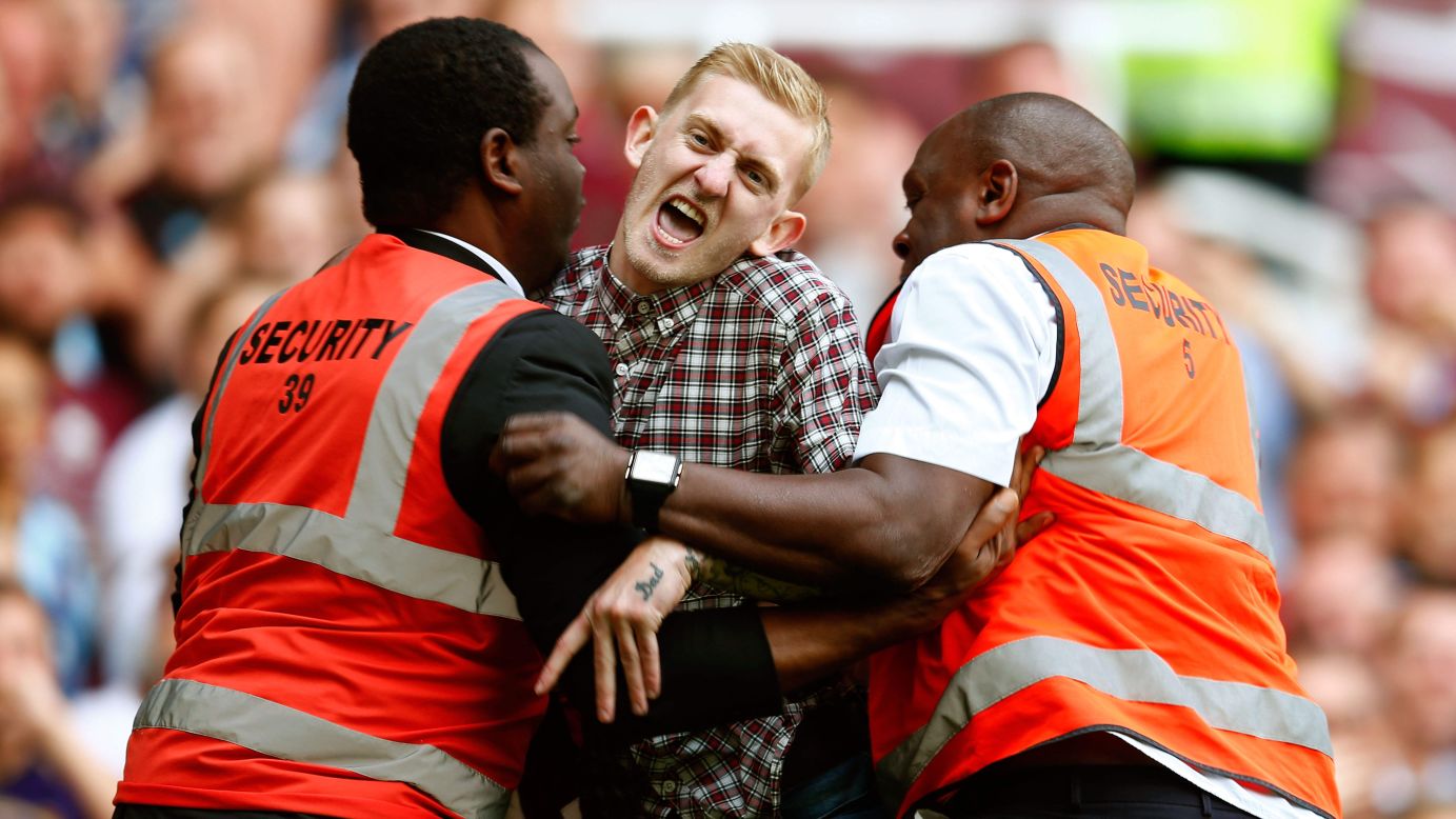 Stewards restrain a man who ran onto the field Saturday, August 16, during the Premier League soccer match between Tottenham and West Ham in London.