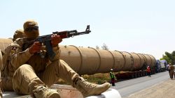 A section of an oil refinery is guarded as it is brought on a lorry to the Kawergosk Refinery, some 20 kilometres east of Arbil, the capital of the autonomous Kurdish region of northern Iraq, on July 14, 2014. The International Energy Agency (IEA) said on July 11, that an offensive by jihadists in northern Iraq had cut output by 260,000 barrels a day in June to 3.17 million, after fighting forced the closure of the country's biggest refinery and slashed production from the giant Kirkuk field