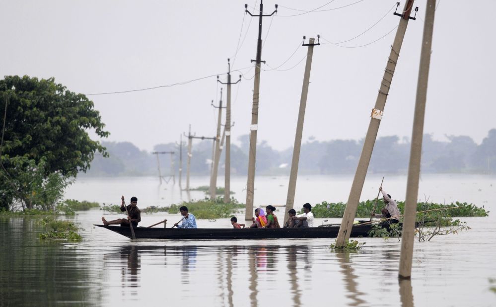 Indian villagers paddle a boat through floodwaters over submerged roads in India's Assam state on Sunday, August 17, 2014. Heavy downpours have triggered flooding that has killed at least 24 people here.