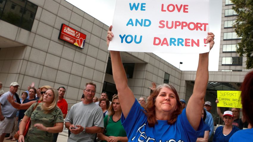 Caption: A woman who did not want to be indentified by name shows her support outside KSDK News Channel 5 on Sunday, August 17, 2014, for Darren Wilson, the Ferguson police officer who shot and killed unarmed teen Michael Brown in Ferguson, Mo. last Saturday. The group of about 100 people were upset that channel 5 ran video footage of Wilson's home and the station later apologized. Protests and tension between police and demonstrators in Ferugson have been ongoing in the St. Louis suburb since the shooting. (Christian Gooden/St. Louis Post-Dispatch/MCT) St. Louis Post-Dispatch/ MCT /LANDOV   Photographers/Source: CHRISTIAN GOODEN/MCT /Landov