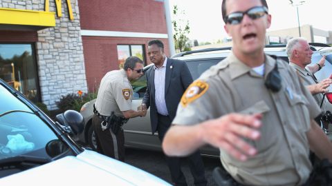 The Rev. Jesse Jackson shakes hands with a police officer as he visits Ferguson's demonstration area on August 18, 2014.