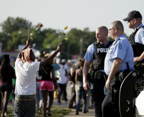 Police watch as protesters march August 19, 2014.