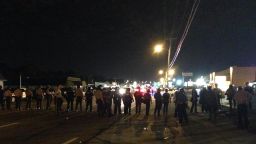 Line of police march wall to wall in Ferguson to clear main drag.