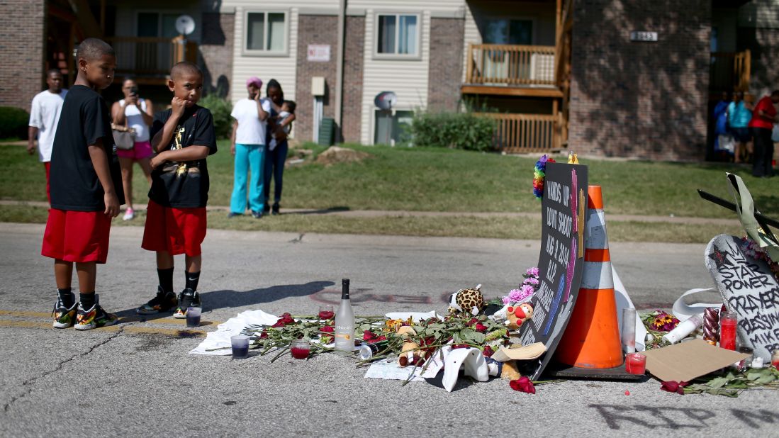 People on August 19 stand near a memorial where Brown was shot and killed, 2014.