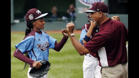 Davis, who pitches for Philadelphia's Taney Dragons, receives congratulations from coach Leland Lott as she returns to the dugout during the shutout game August 15 against South Nashville.