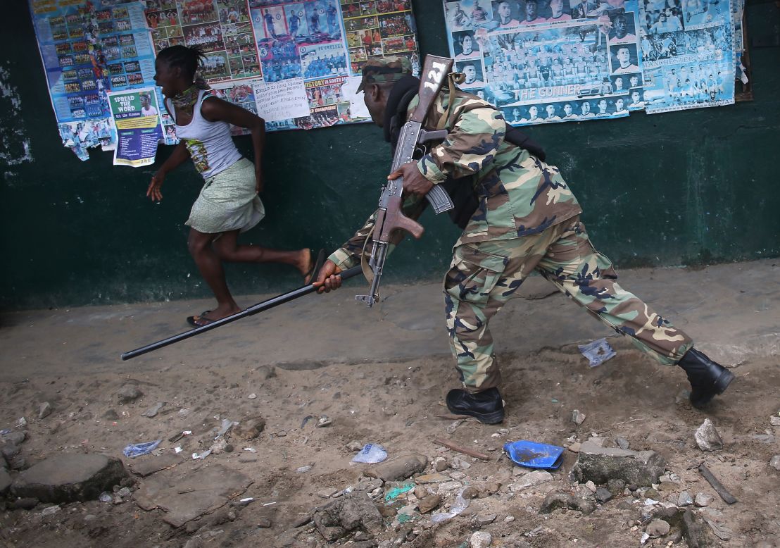 An Ebola Task Force soldier beats a local resident while enforcing a quarantine on the West Point slum on August 20, 2014.