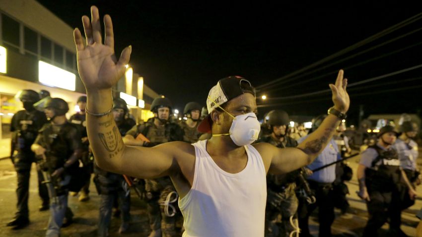 A man is moved by a line of police as authorities disperse a protest in Ferguson, Mo. early Wednesday, Aug. 20, 2014. On Saturday, Aug. 9, 2014, a white police officer fatally shot Michael Brown, an unarmed black teenager, in the St. Louis suburb. (AP Photo/Charlie Riedel/AP)