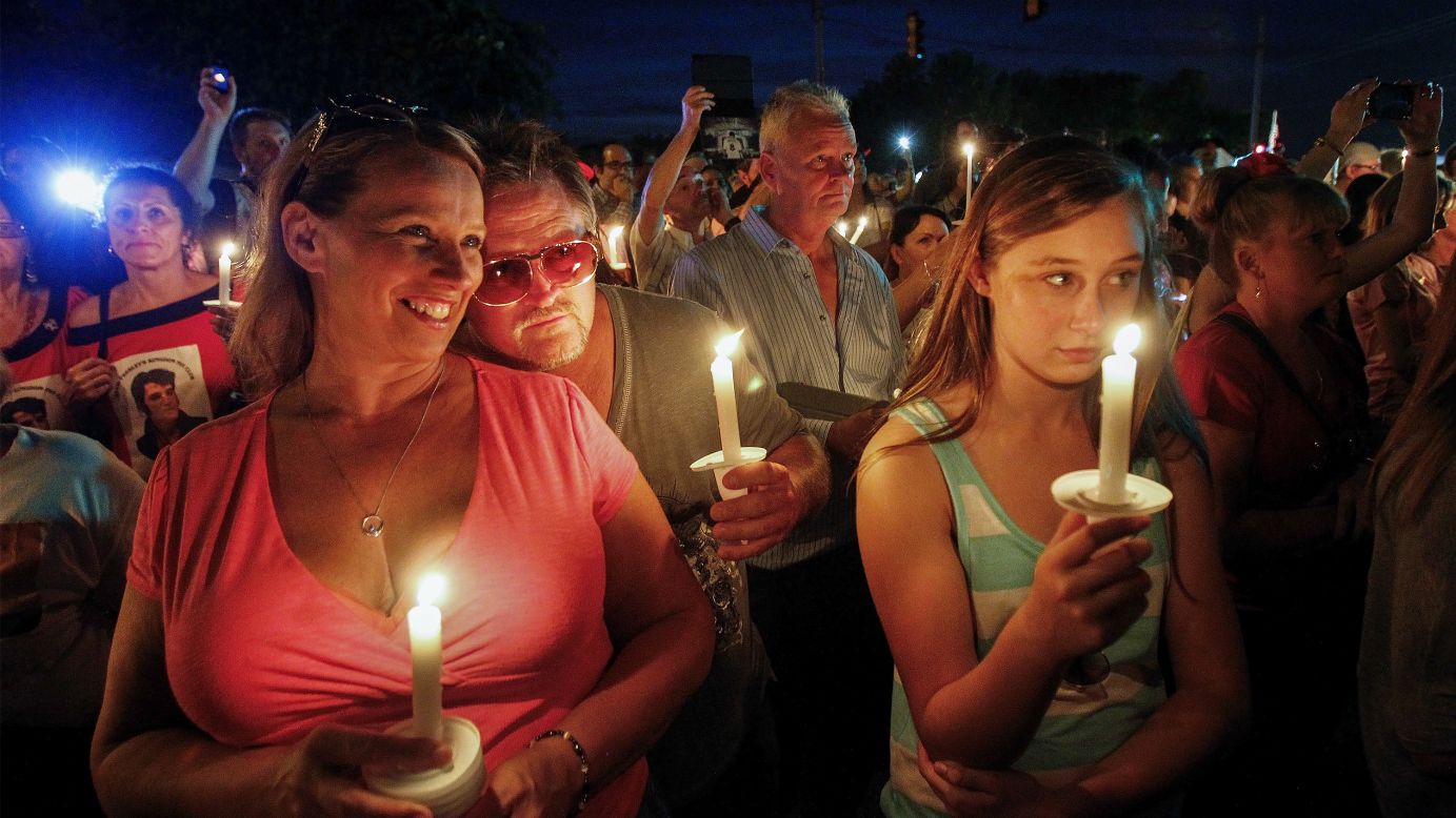 Sharon Kestner, left, enjoys the sounds of Elvis Presley during a candlelight vigil held Friday, August 15, outside the gates of Graceland, Presley's estate in Memphis, Tennessee. People gathered there in remembrance of Presley's death 37 years ago.